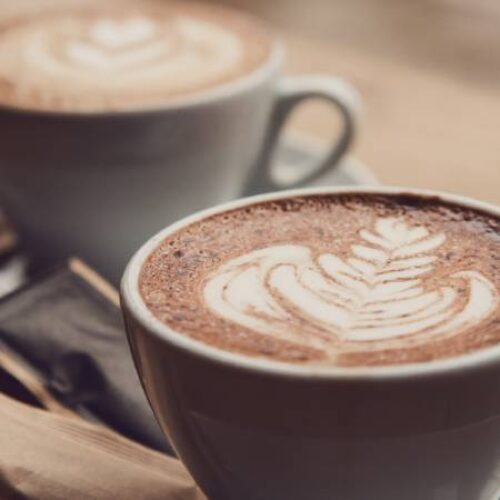 a pair of coffee mugs topped with foam flowers