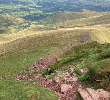 Looking downhill in the Brecon Beacons with people walking up for Cancer Research UK’s Big Hike