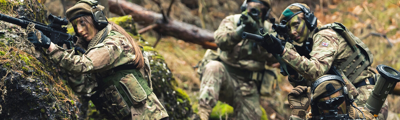 Female veterans take aim with their guns in a forest