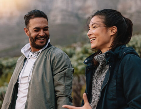 Portrait of happy young couple walking and talking in the countryside. Young man and woman enjoying on a nature hike.